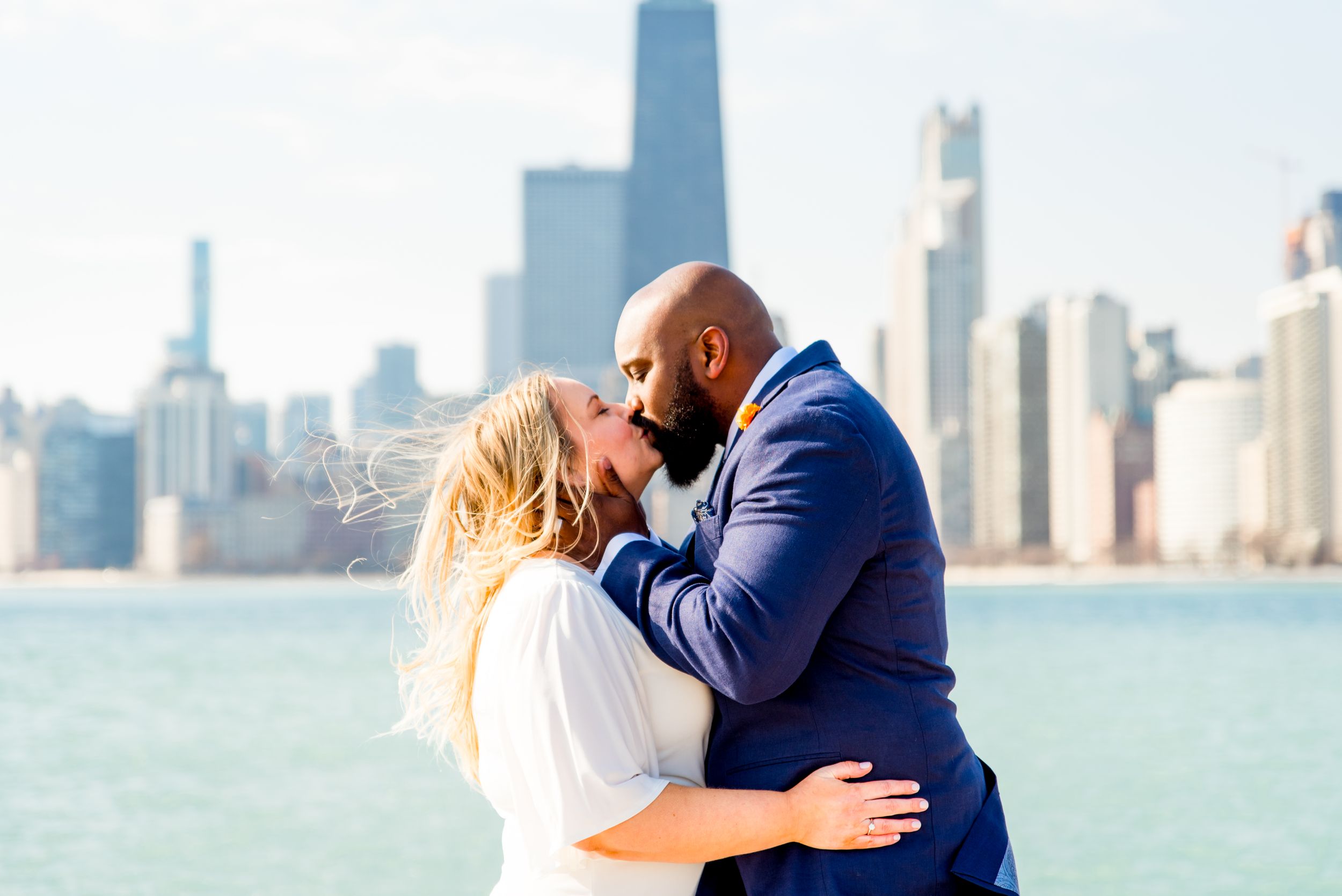 blonde woman and man with beard in navy suit kissing on pier at north avenue beach after chicago elopement