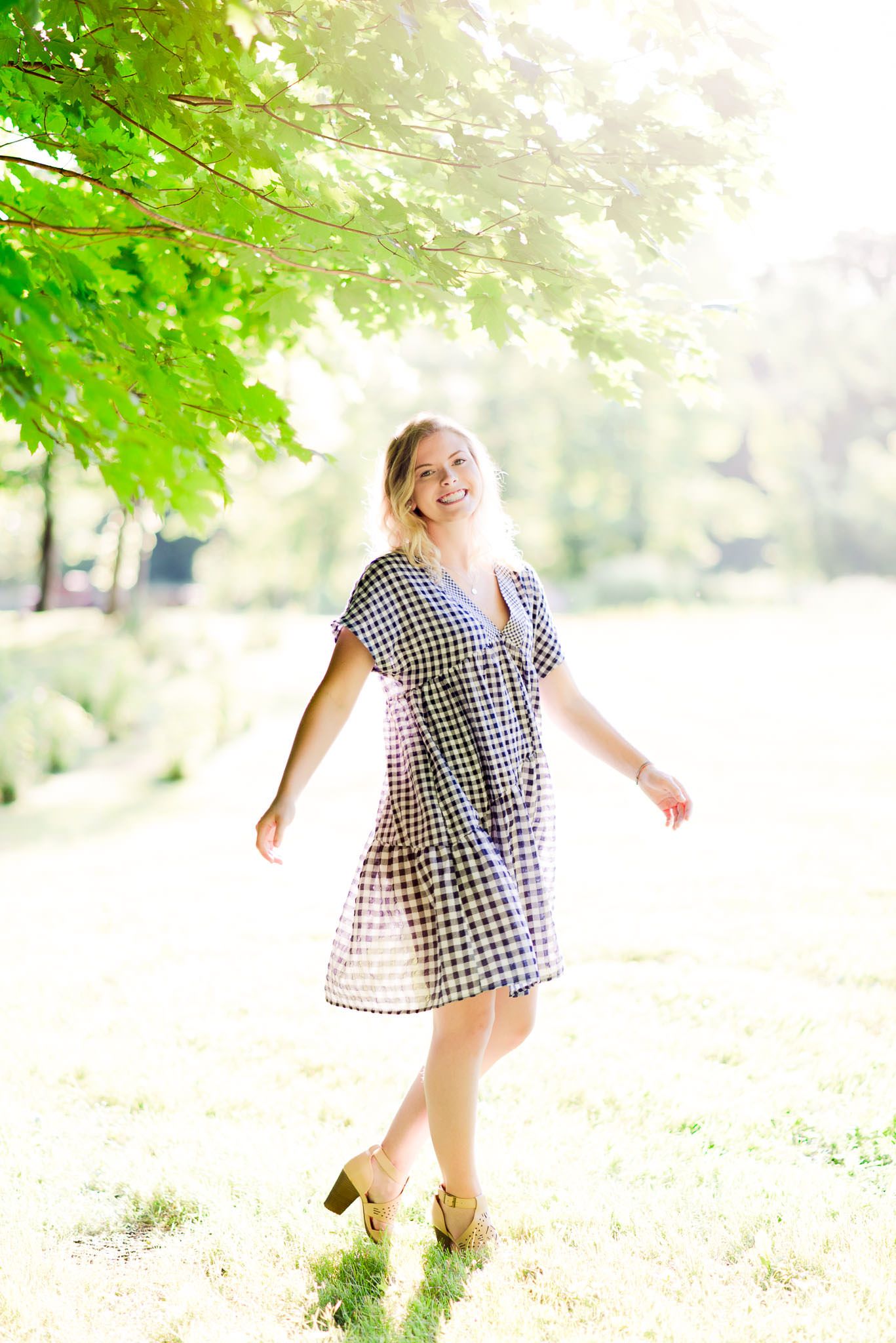 blonde young woman spinning in blue and white dress at sunset at the Marmalade Lily in Cincinnati, OH for senior picture