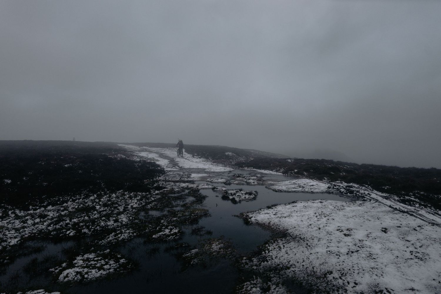 Aerial view of a snowy coastal landscape with dramatic cloudy skies.
