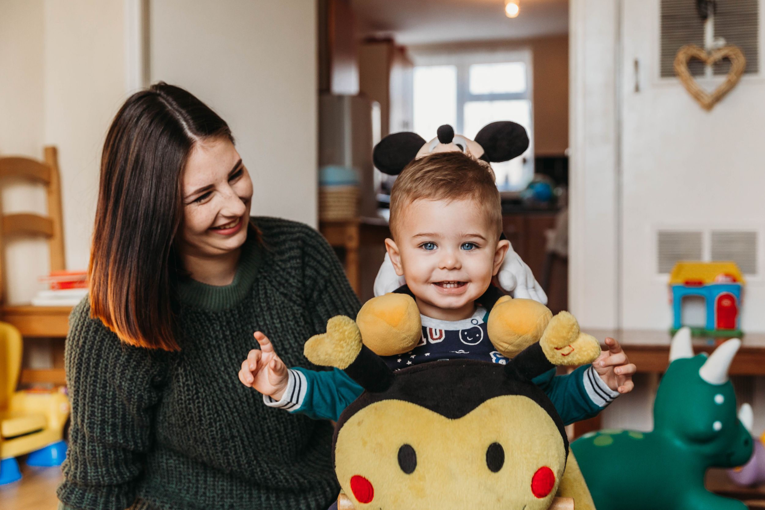 little boy on rocking horse with mum smiling