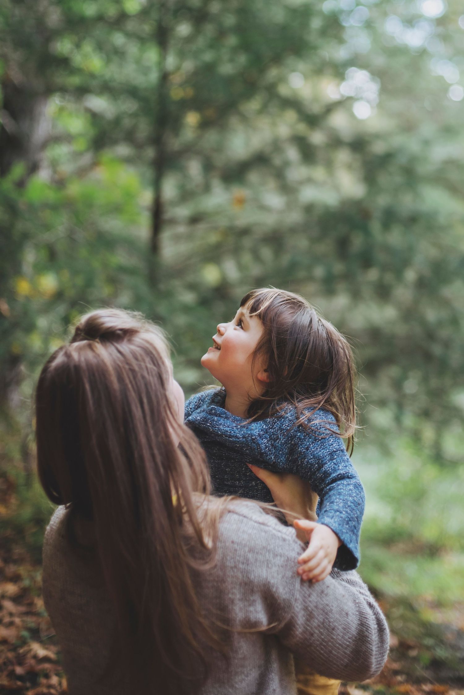 A touching moment between parent and child in a forest setting.