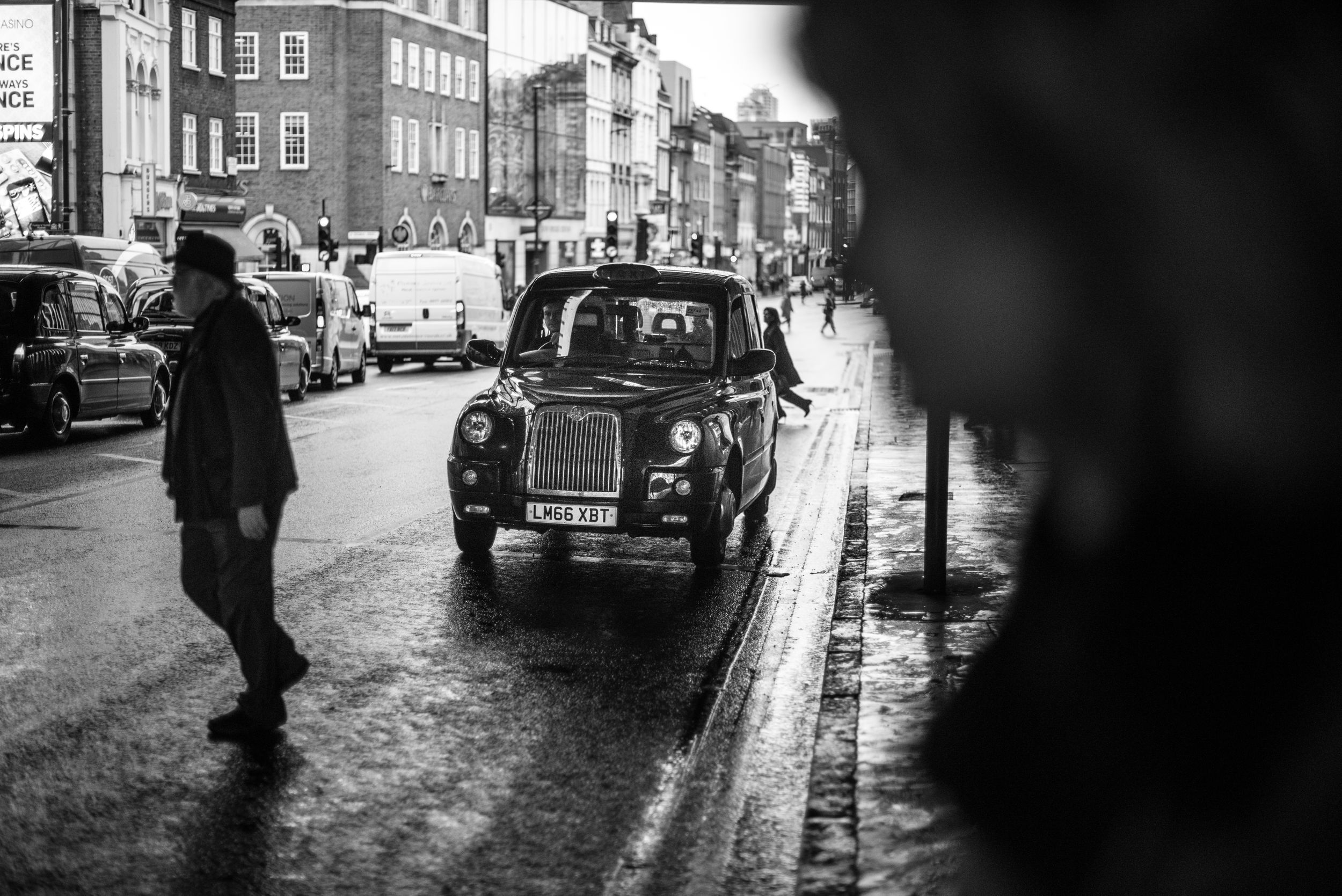 b&w street image in London of people crossing the street in front of a taxi