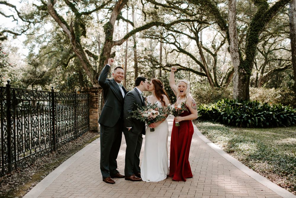 couple sharing a kiss while their wedding party cheers them on