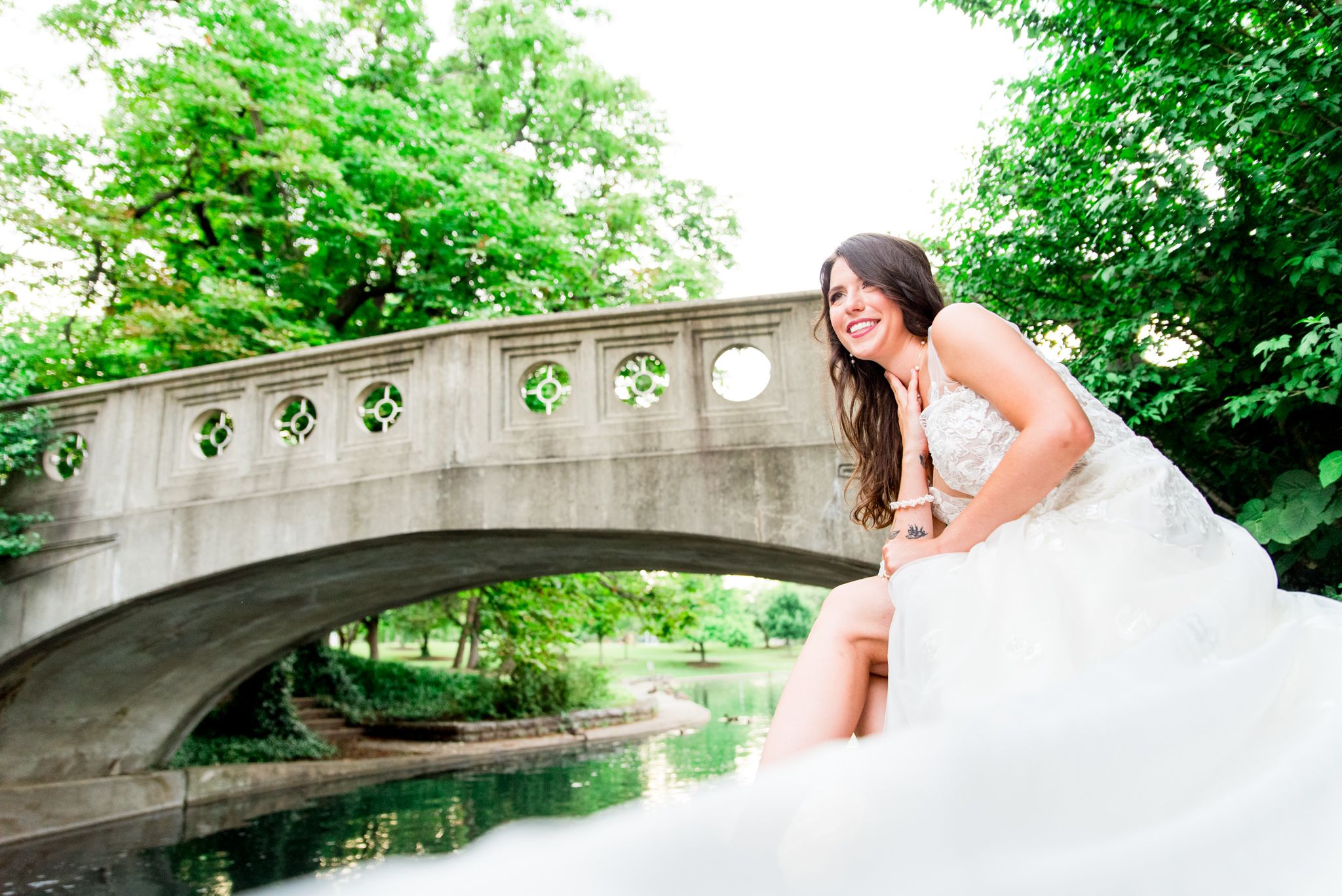 bride smiles and leans on hand under bridge at Eden Park for summer wedding in Cincinnati ohio
