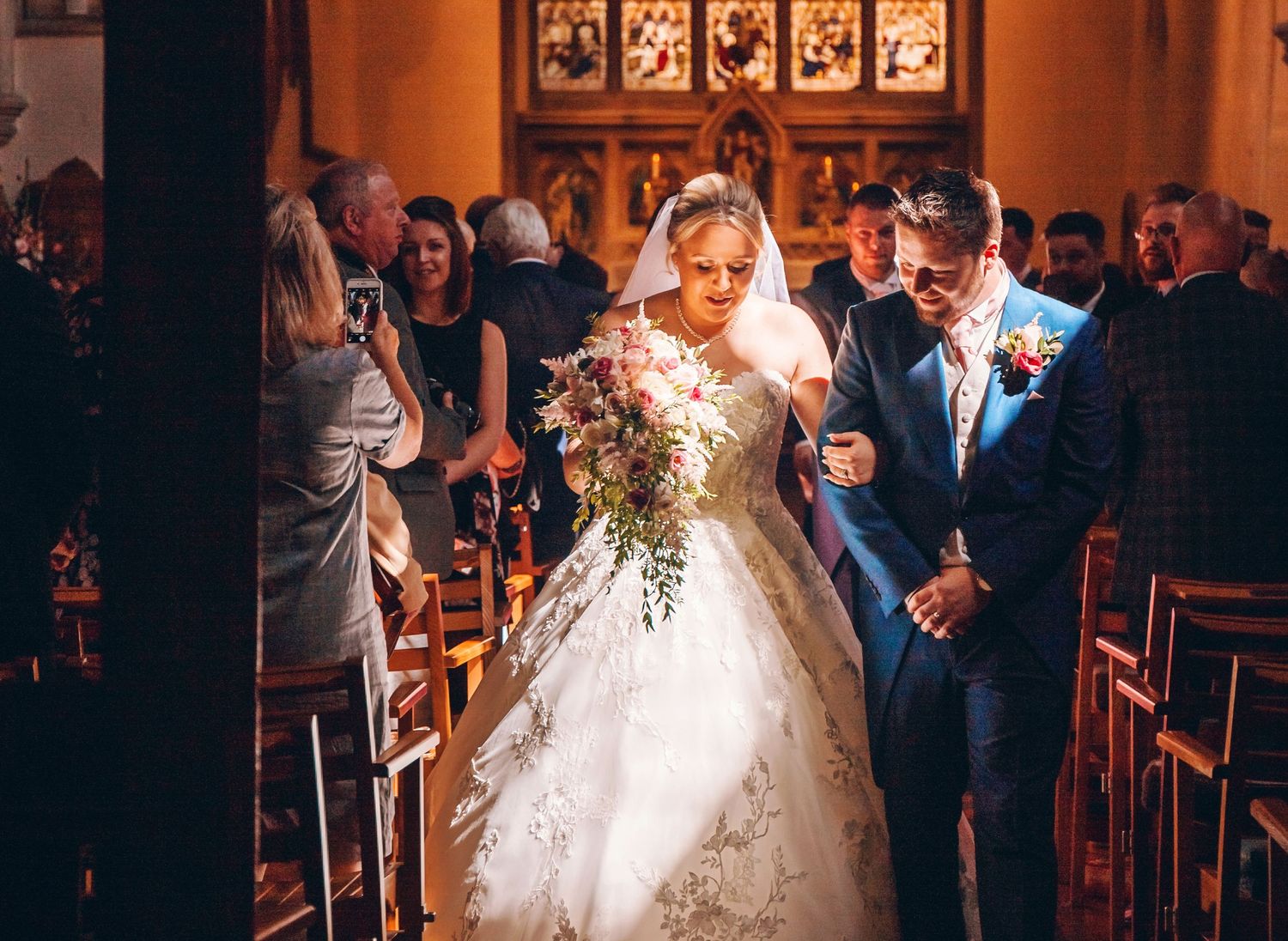 bride and groom leaving church with strong sun beam across their faces