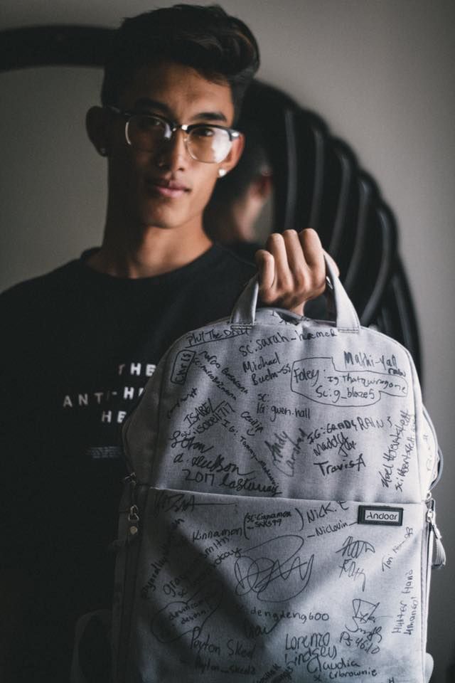 Shounam Ches holding up an affordable camera Amazon backpack with Young Life camp staff and visitor signatures