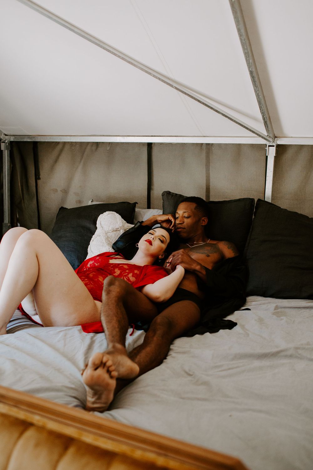 man and woman laying on a bed intertwining hands during their couples boudoir session