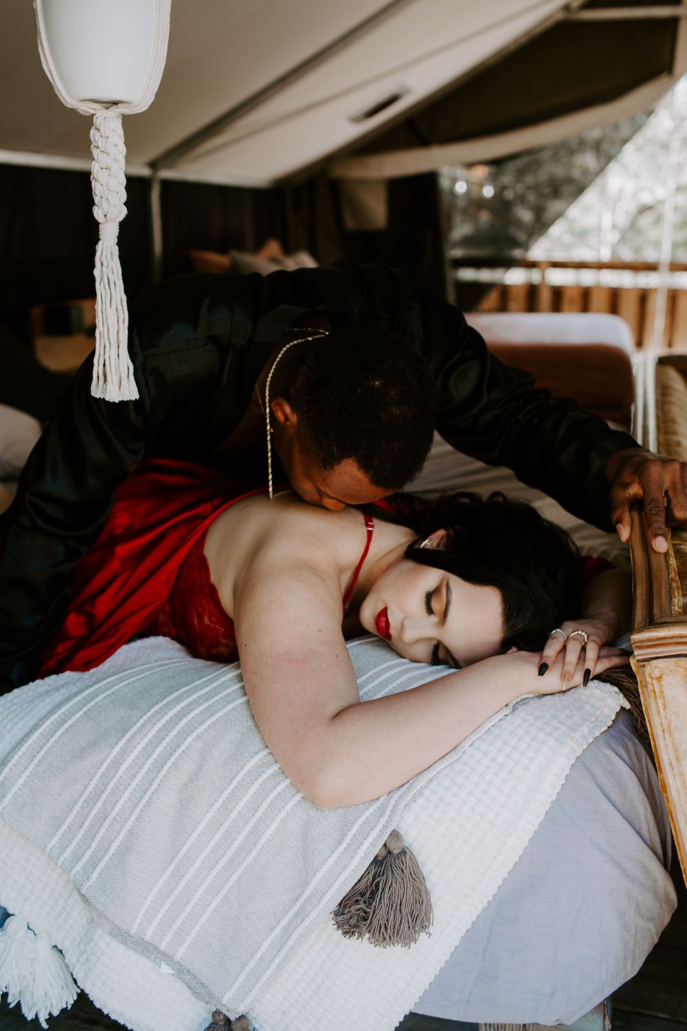man kissing woman's back as she lays on their bed during their intimate couples session