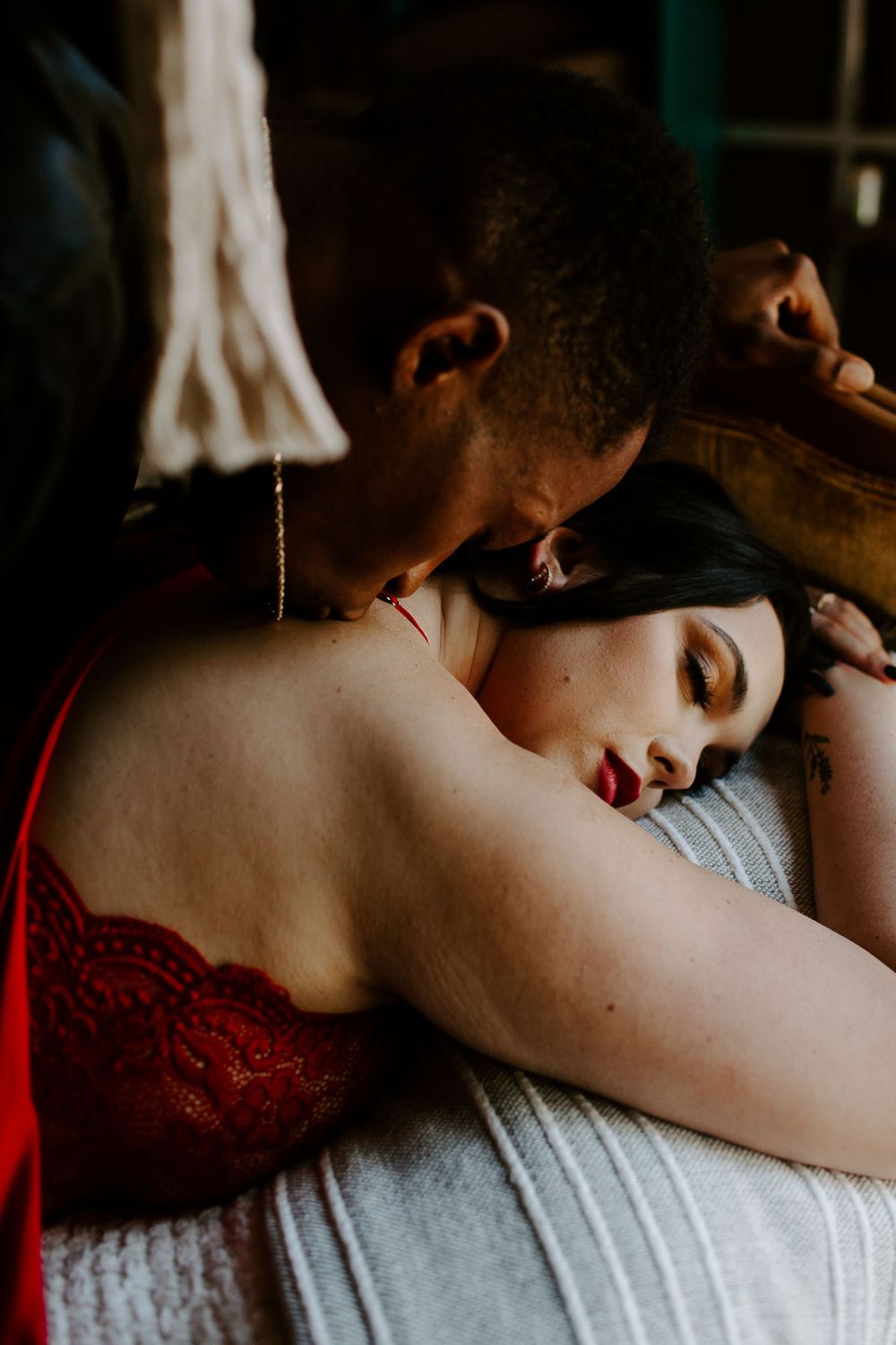 man kissing woman's back while she is closing her eyes during their intimate couples session