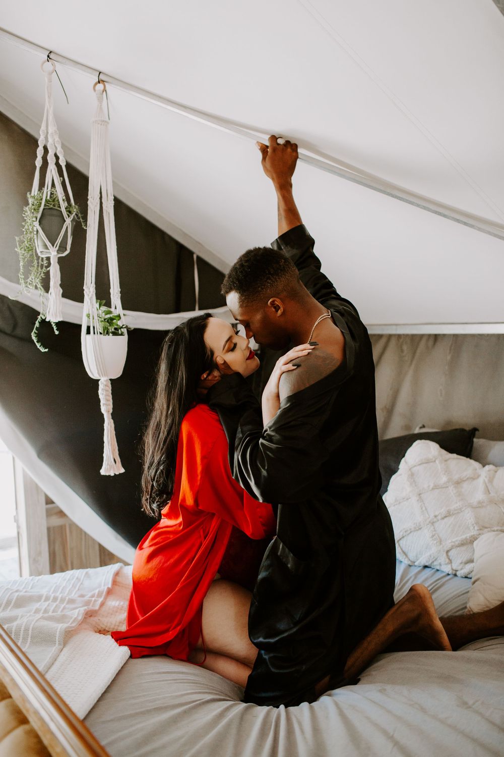 man and woman kneeing on a bed about to kiss during their intimate couples session