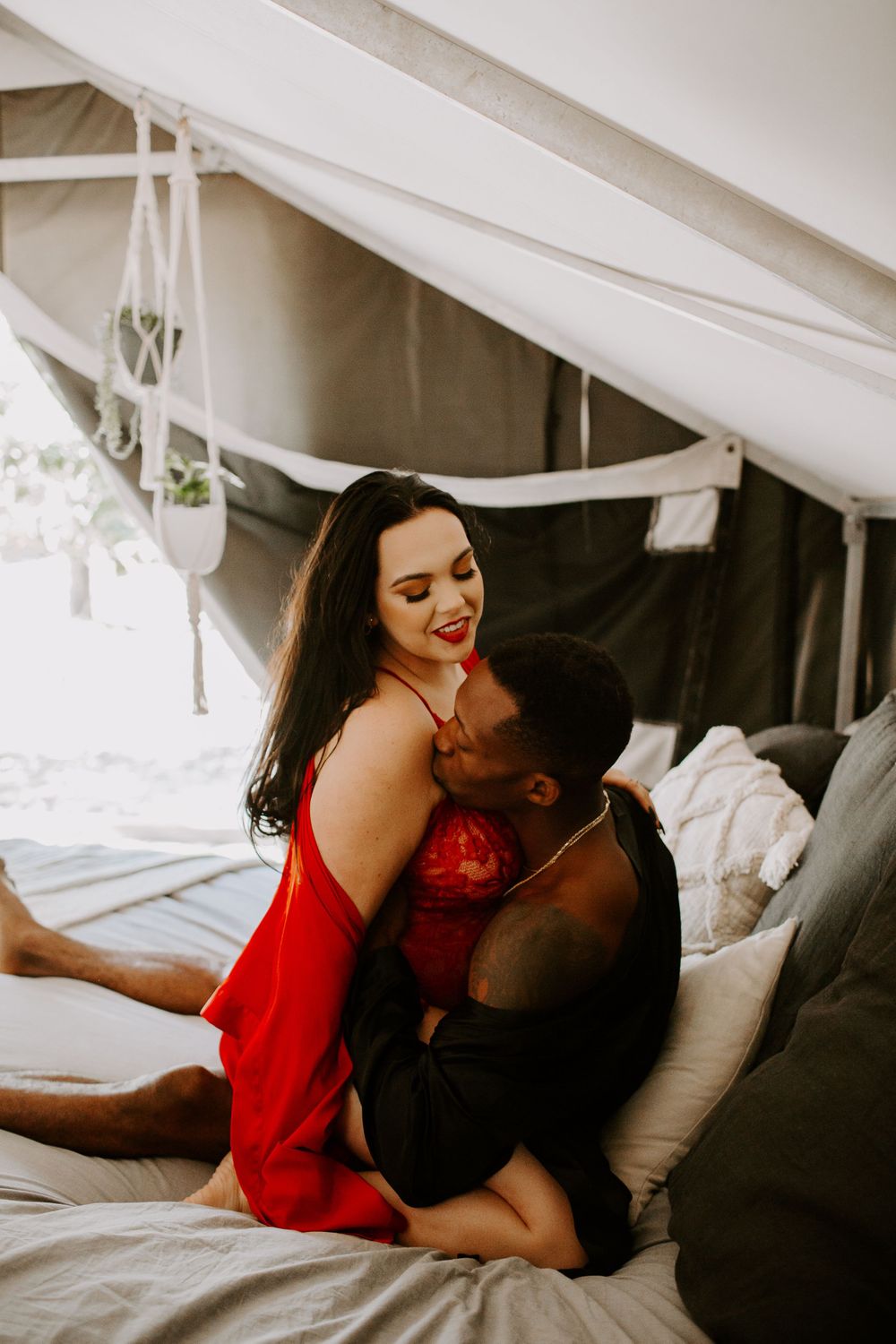 man kissing a woman's shoulder while the woman is laughing during their couple session