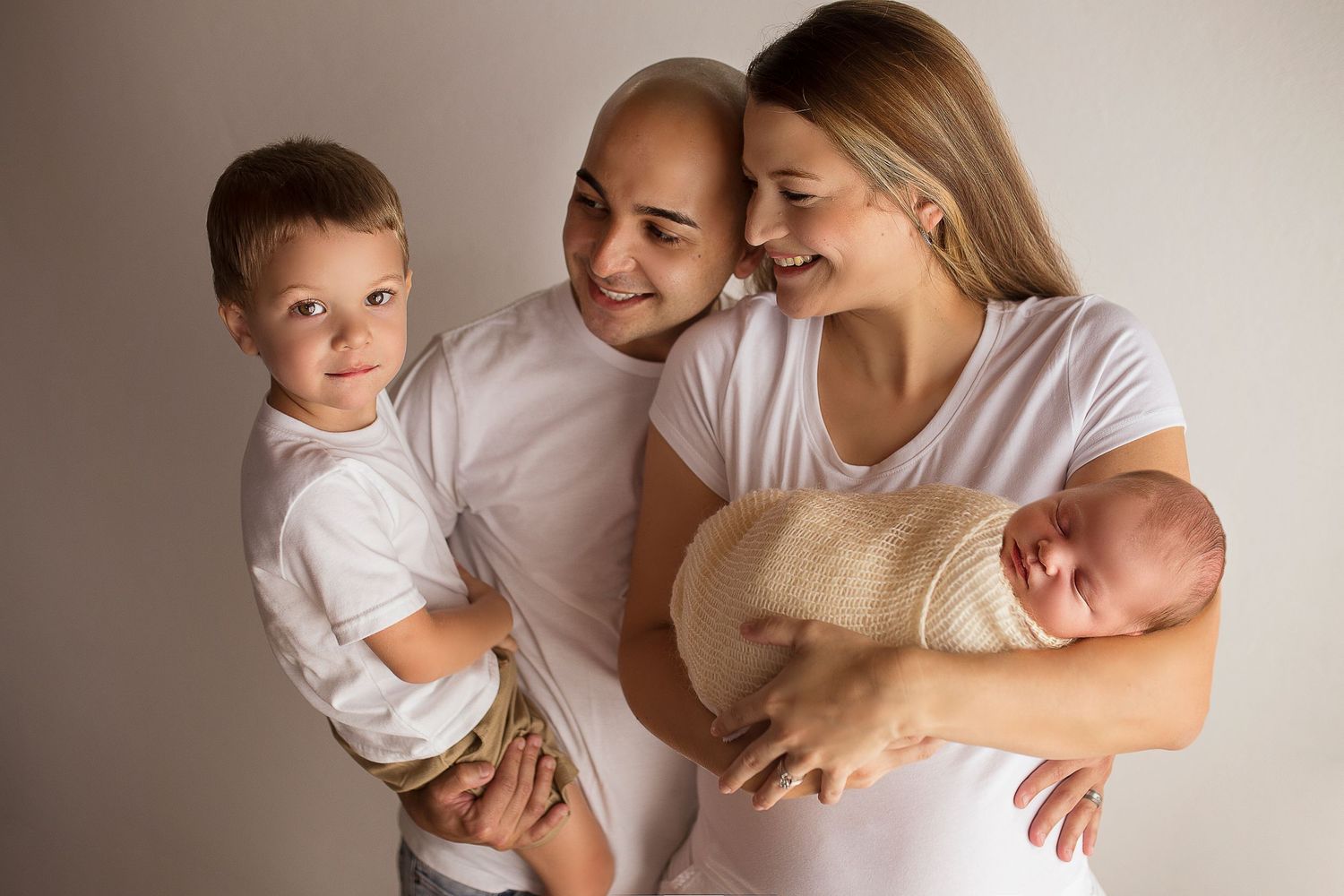 parents of two boys looking at big brother while holding baby brother