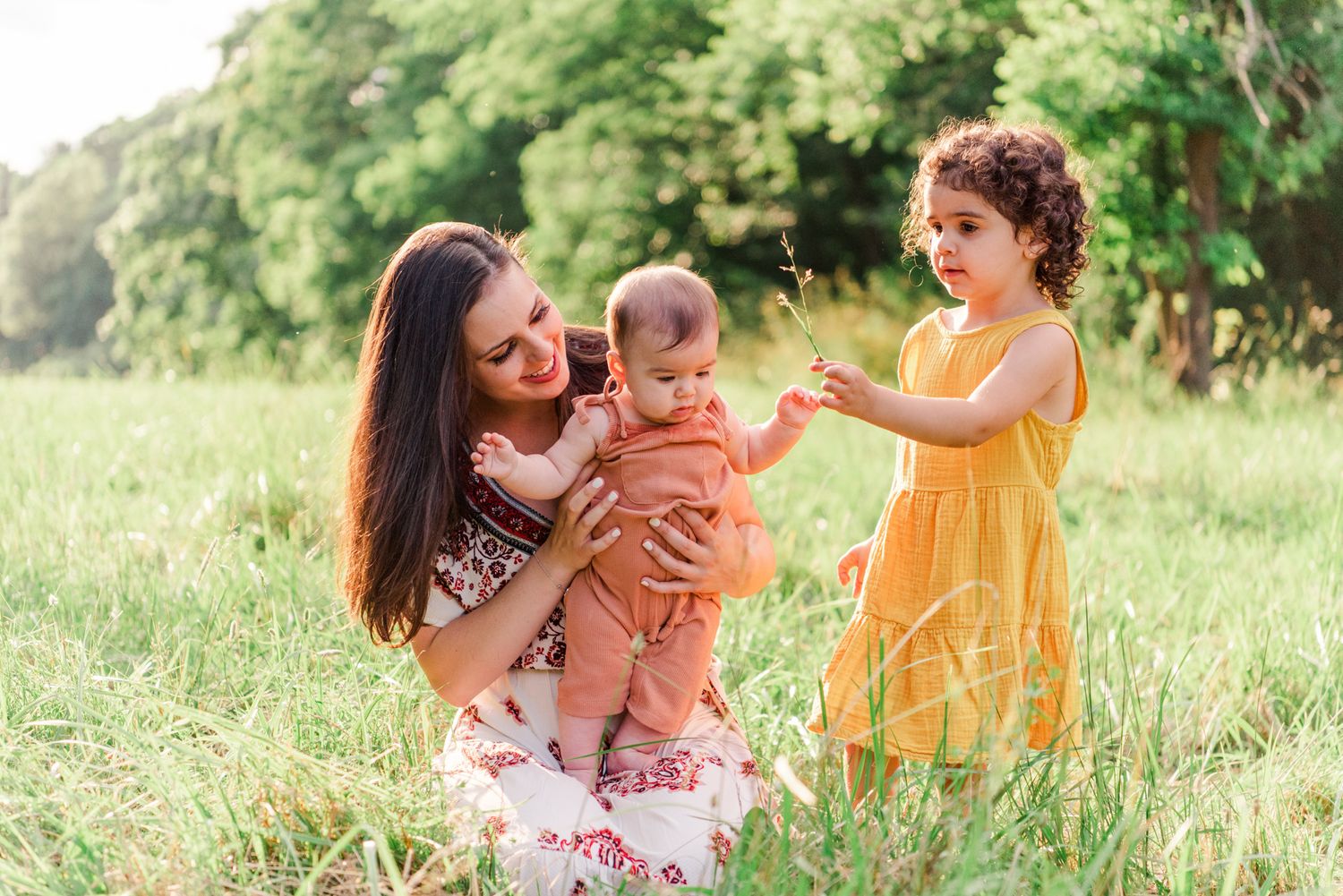 Mother playing with young daughters in field in Pittsburgh, Pennsylvania