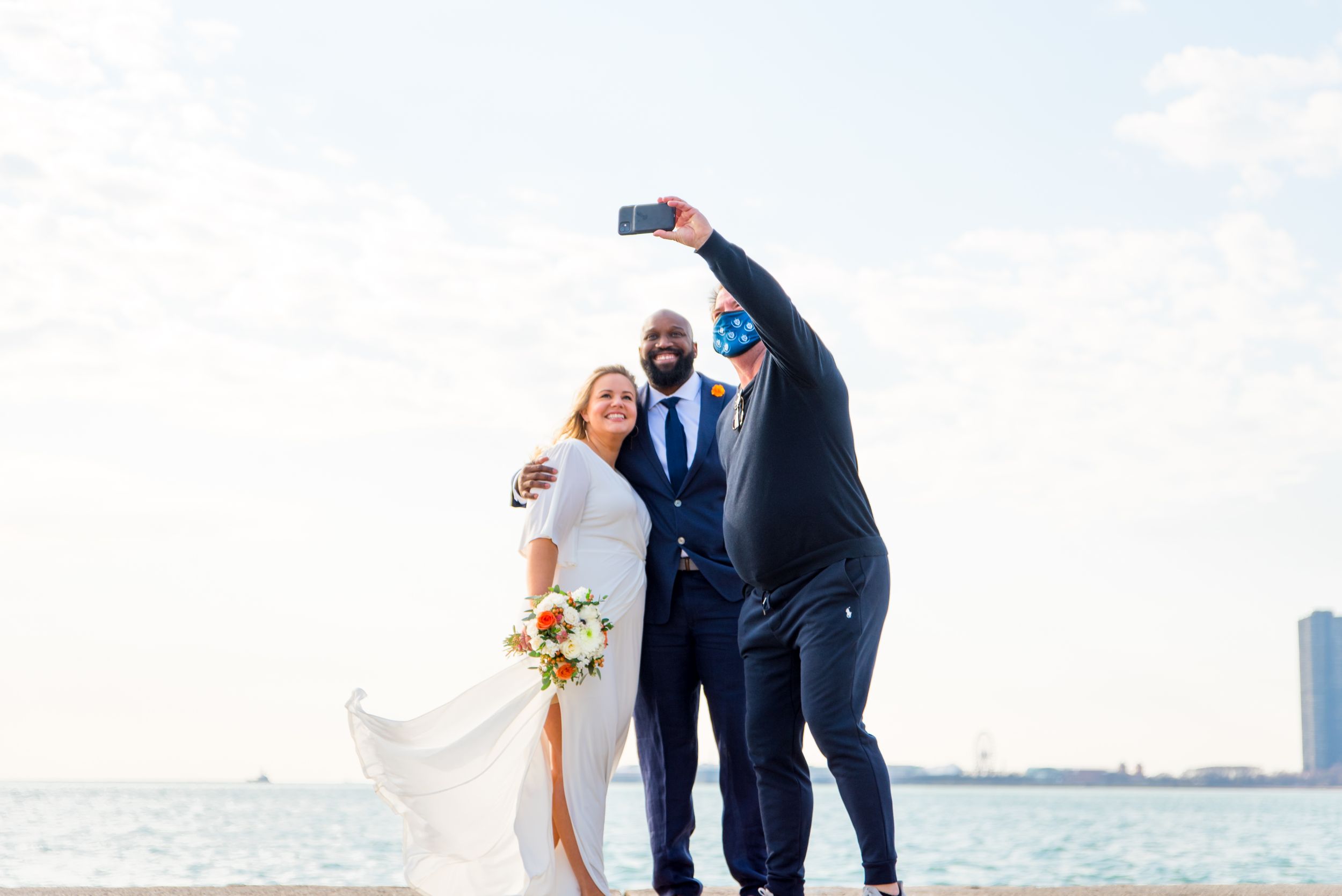 wedding pictures at north avenue beach chicago couple taking selfie with someone passing by