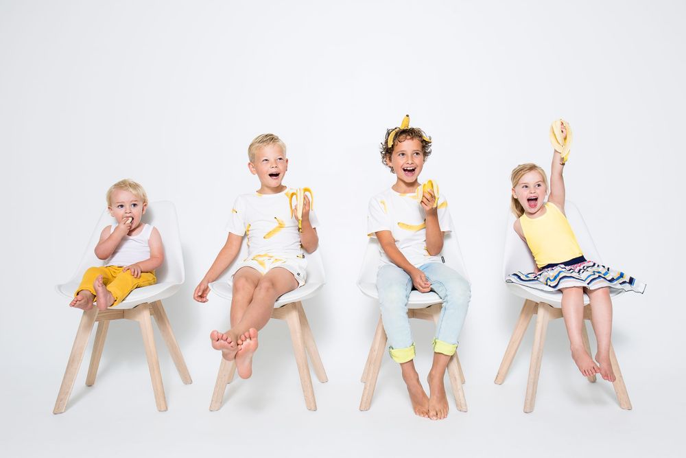 Kinderen met bananen in hun handen op stoelen in de studio