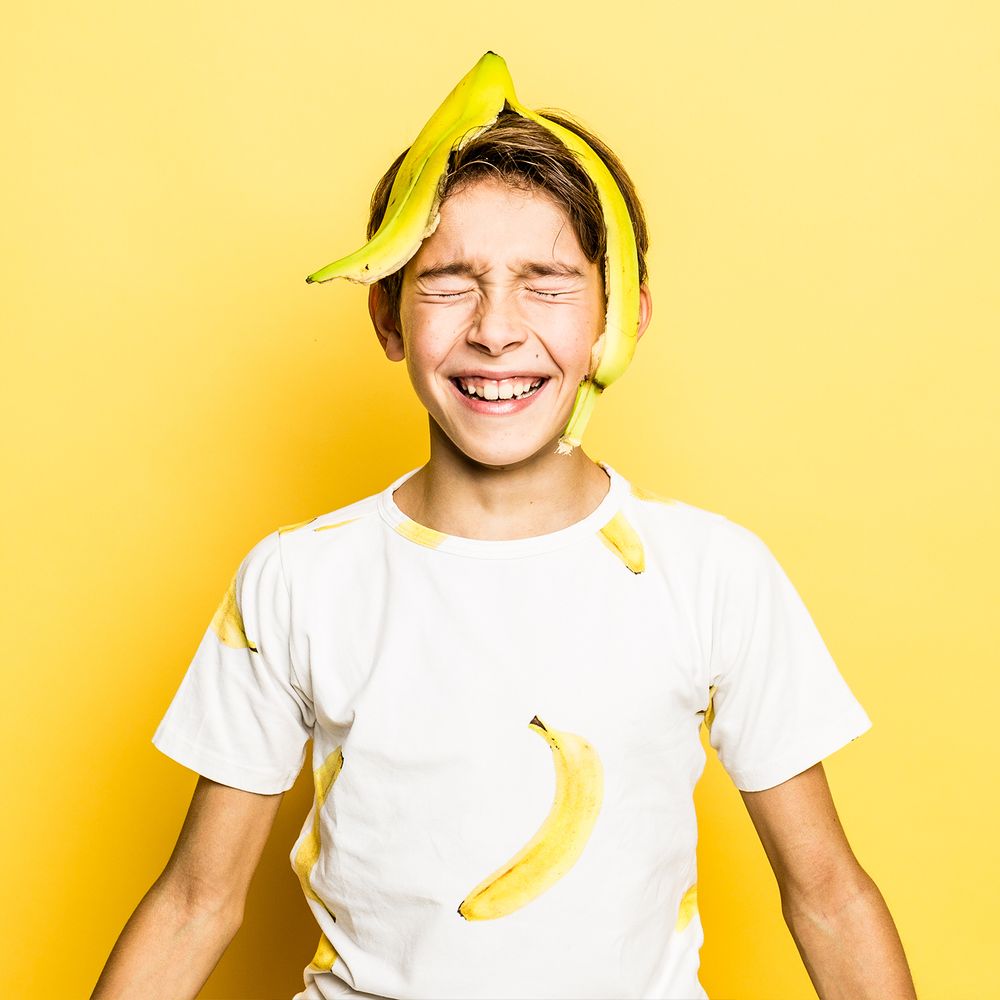 Jongen met banaan in de studio met gele achtergrond