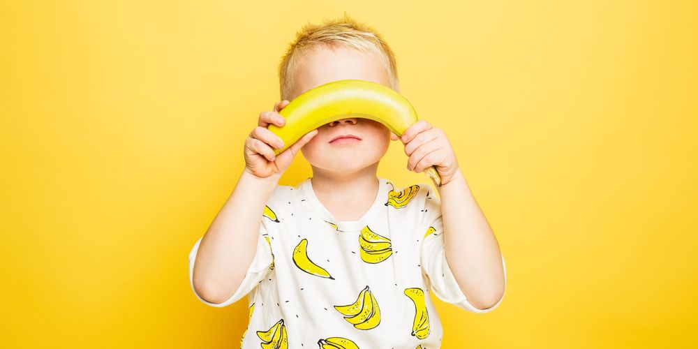 Jongen met banaan in de studio met gele achtergrond