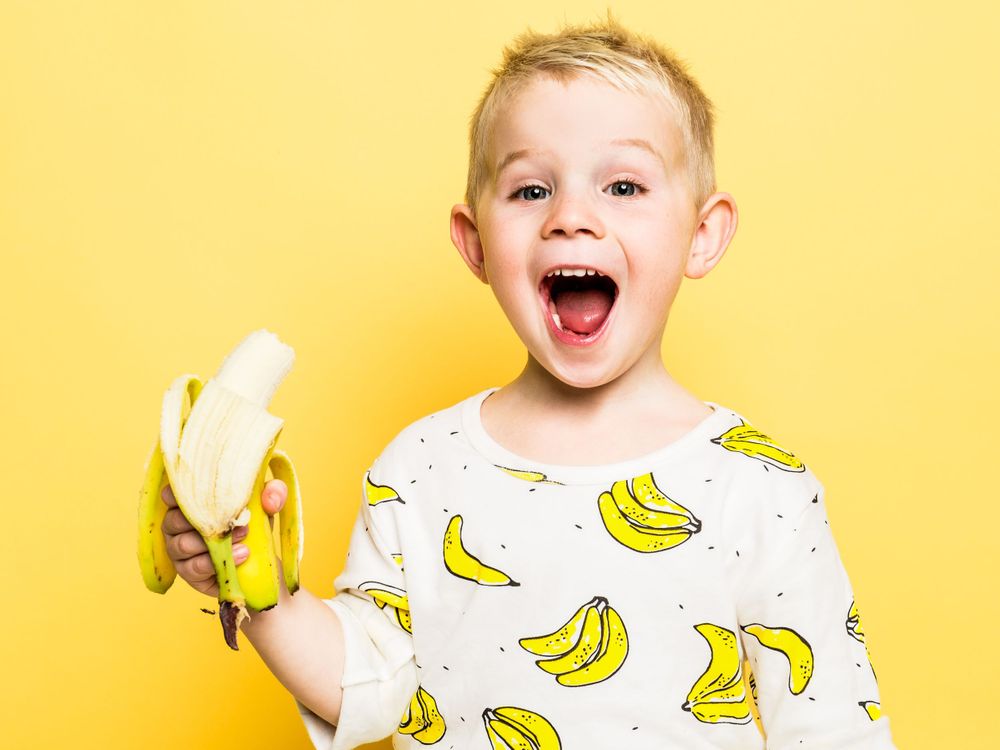 Jongen met banaan in de studio met gele achtergrond