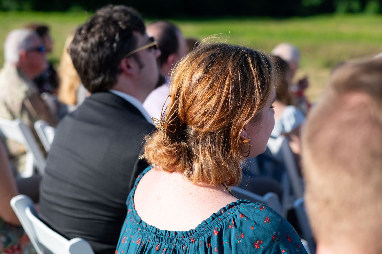 Close-up of wedding guests watching outdoor ceremony in summer.