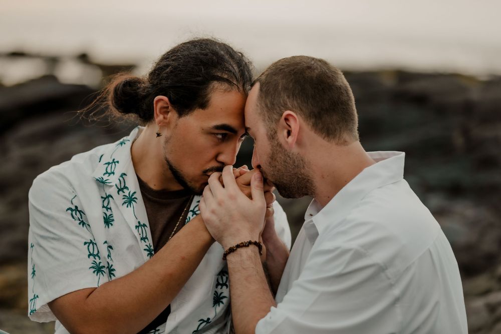 A tender moment between two people on a rocky beach at sunset.