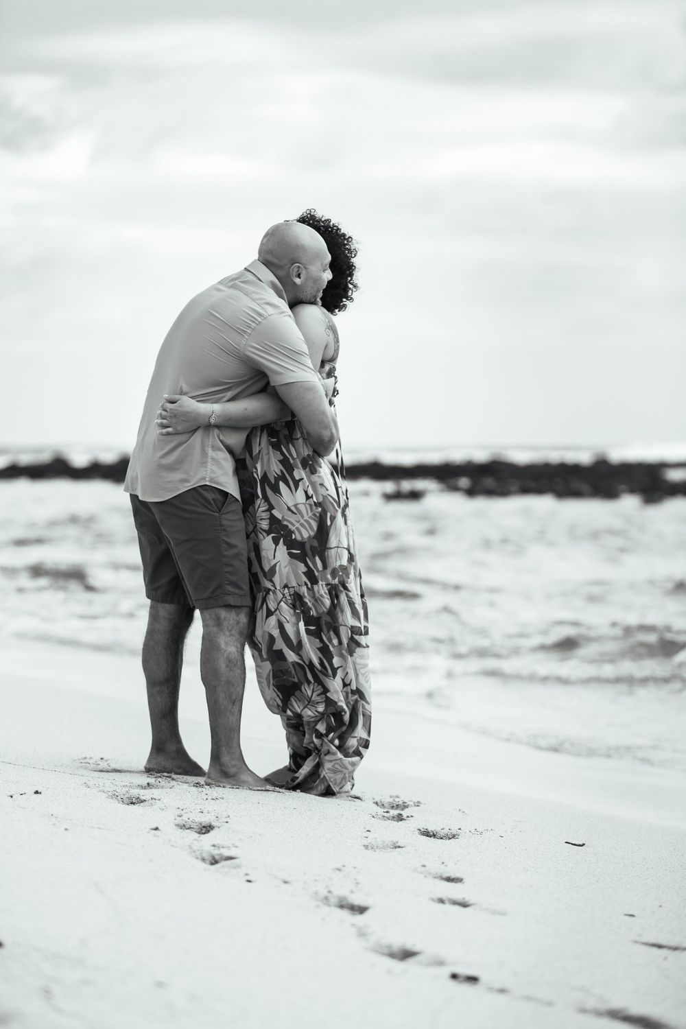 A couple embracing on a beach in black and white photography.