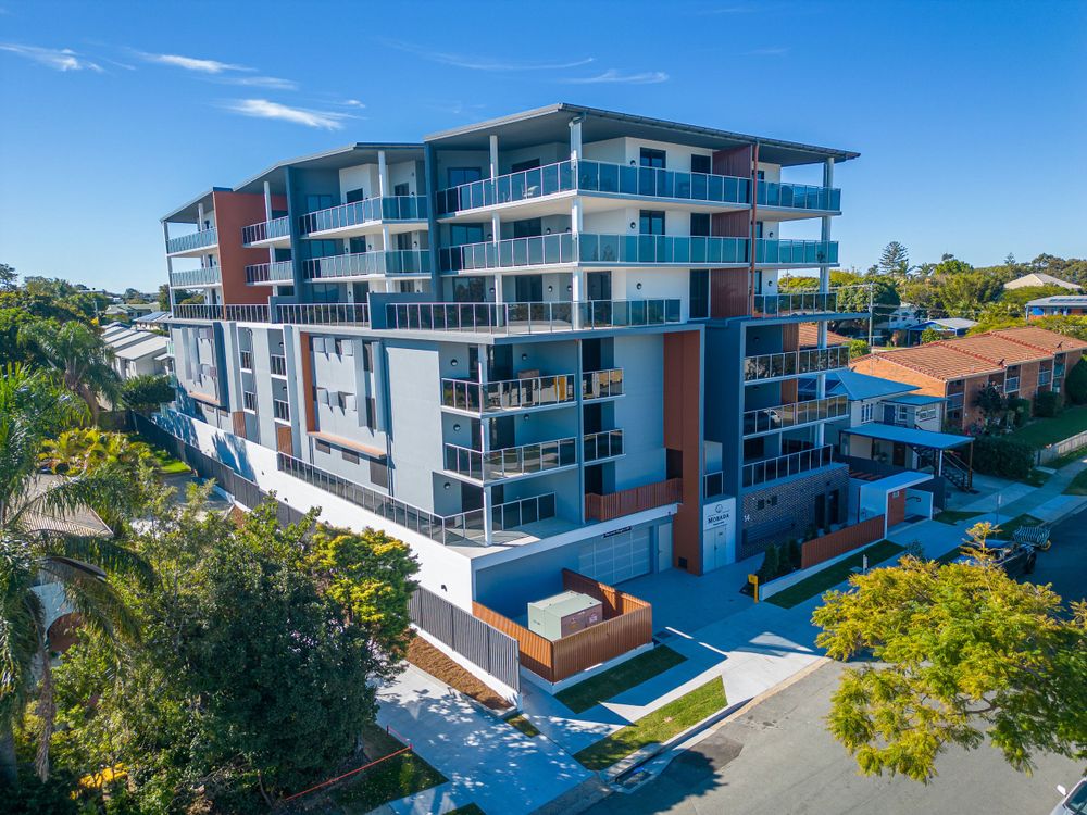 Contemporary multi-story residential building with glass balconies and modern architecture.