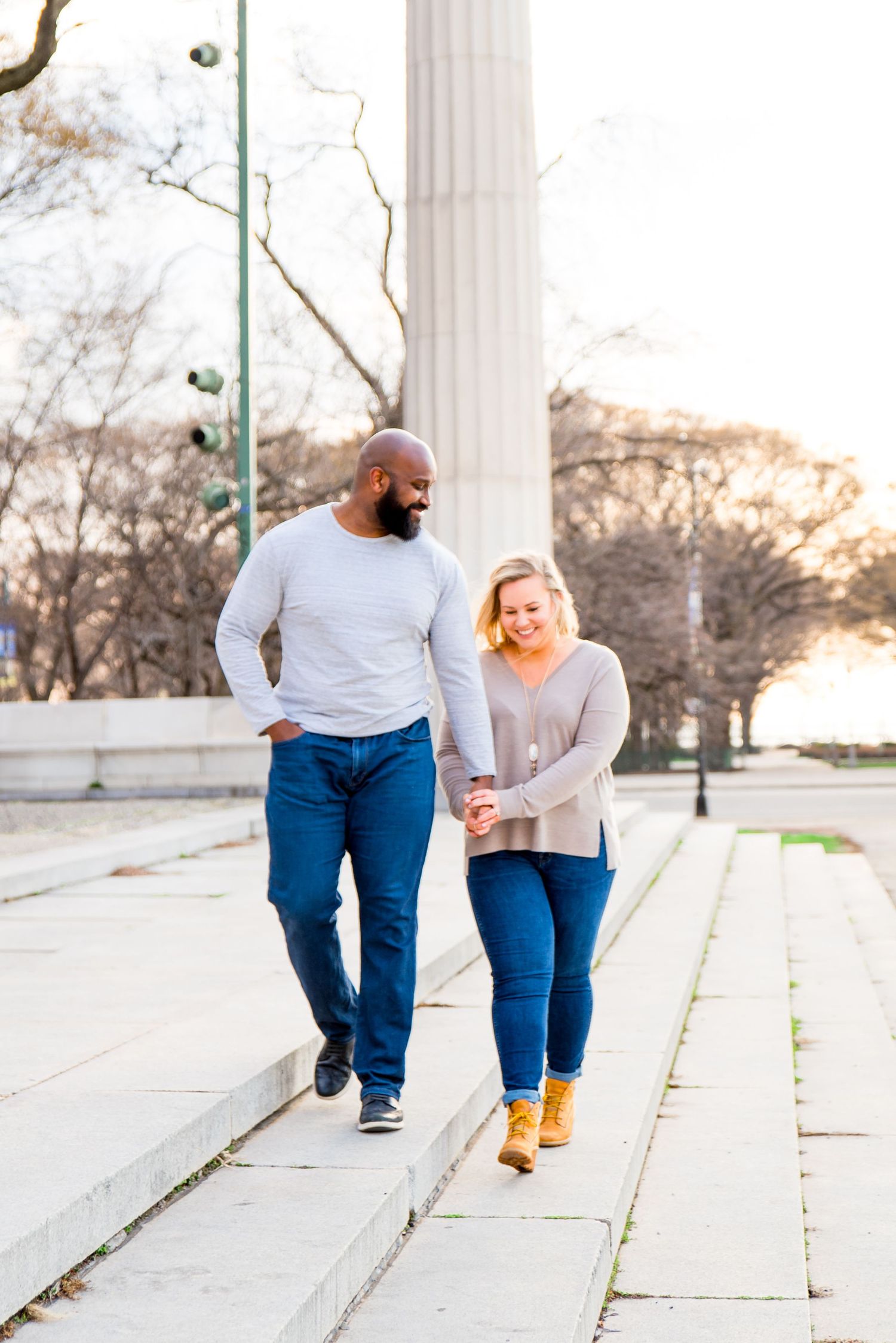 man and woman holding hands laughing in Grant Park sunrise engagement pictures in Chicago