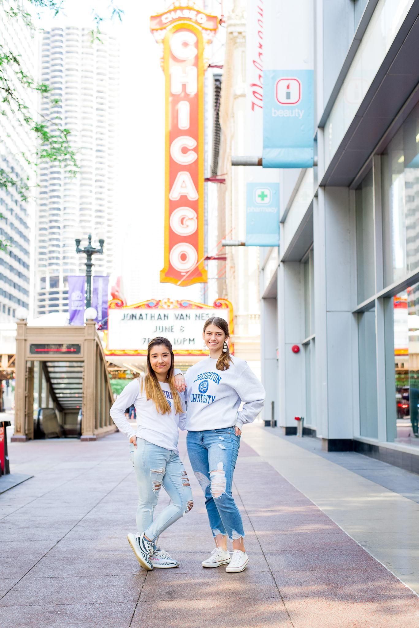 two senior girls in front of the Chicago Theater sign for Chicago senior pictures back to back