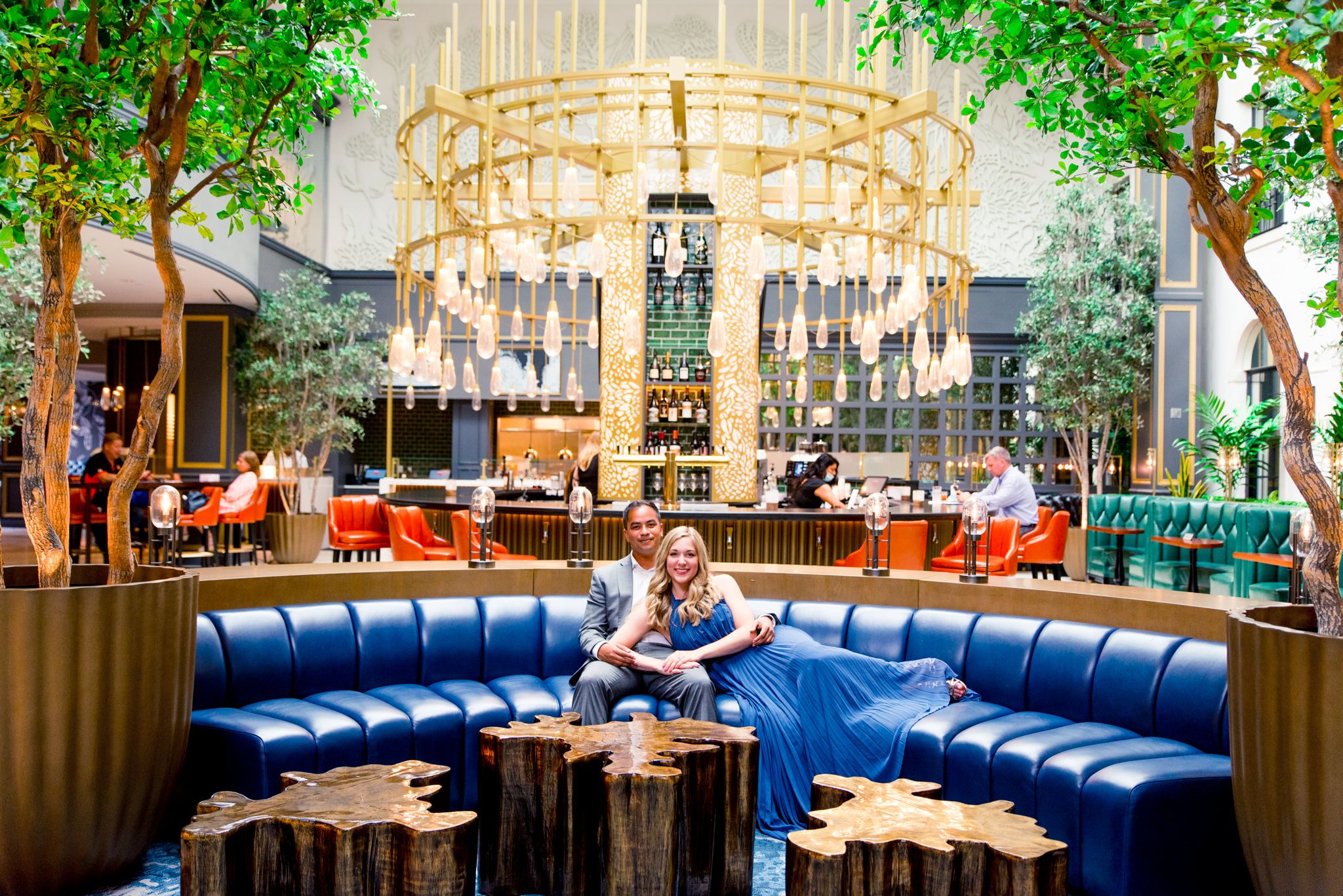 man in gray suit and woman in blue dress on couch at Lytle Park Hotel main atrium