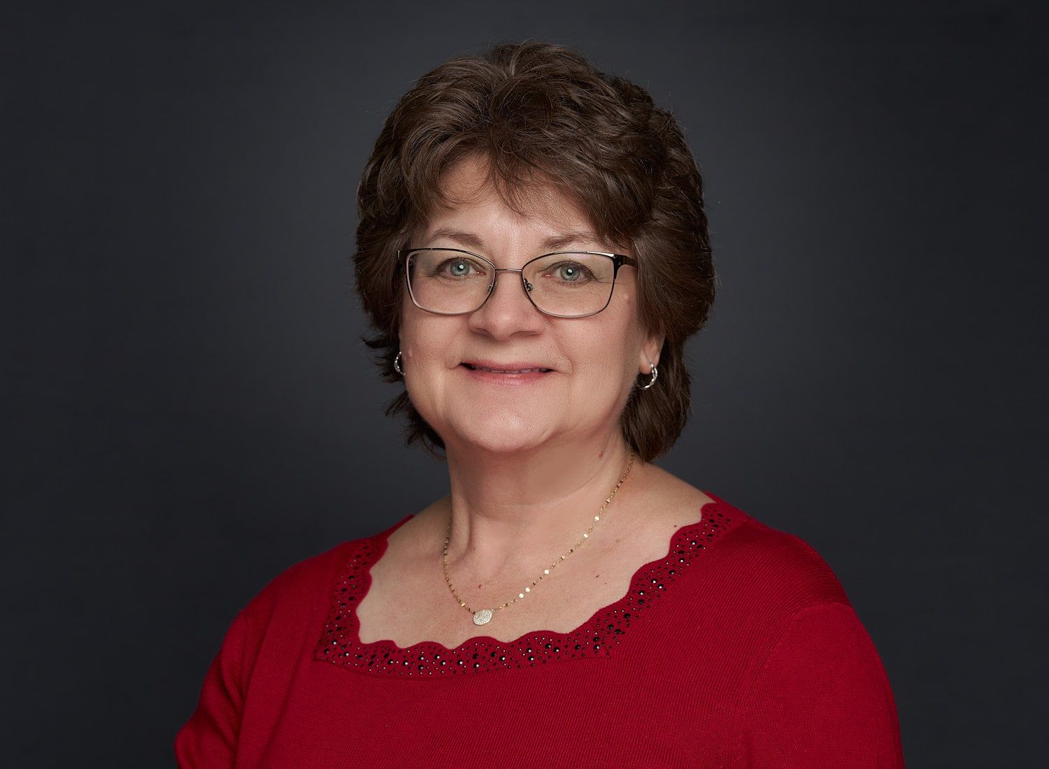 Headshot of middle-aged woman with short, coiffed brown hair in red sweater