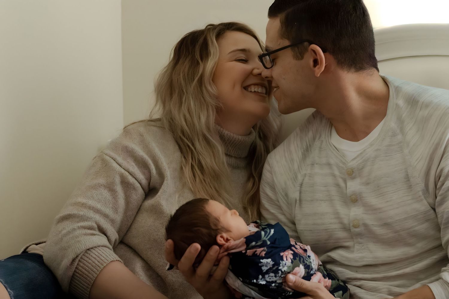 Mom and Dad kissing with newborn