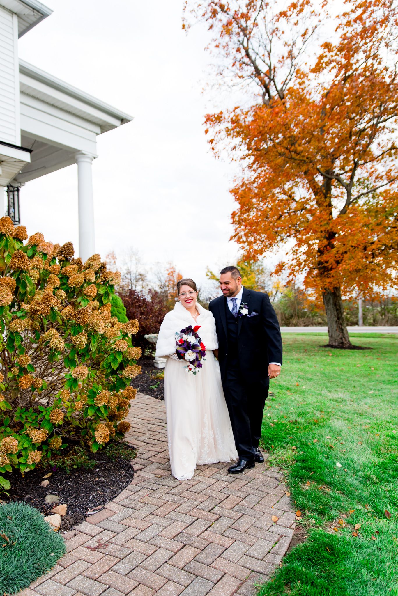 bride and groom walking in front of white house and orange tree at Shepard's Place wedding in Ohio