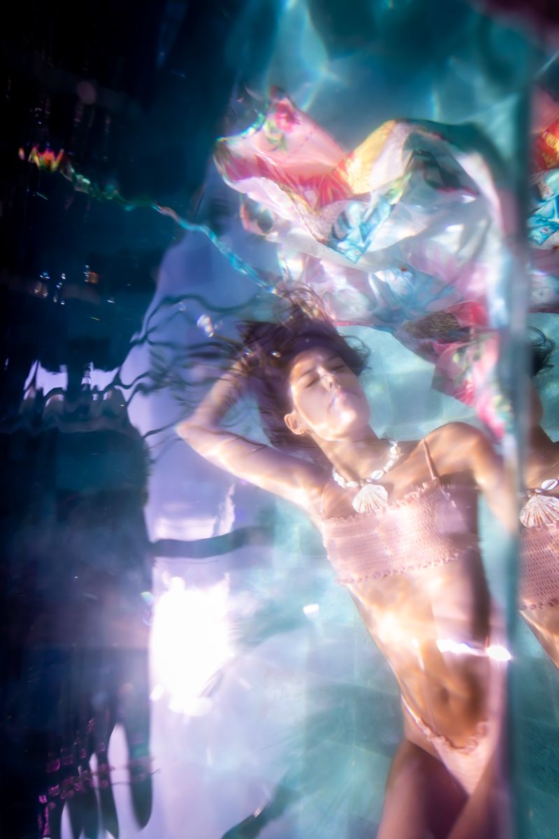 A woman's reflection in a pink bikini through water