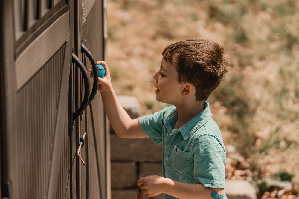 young boy hunting easter eggs by shed