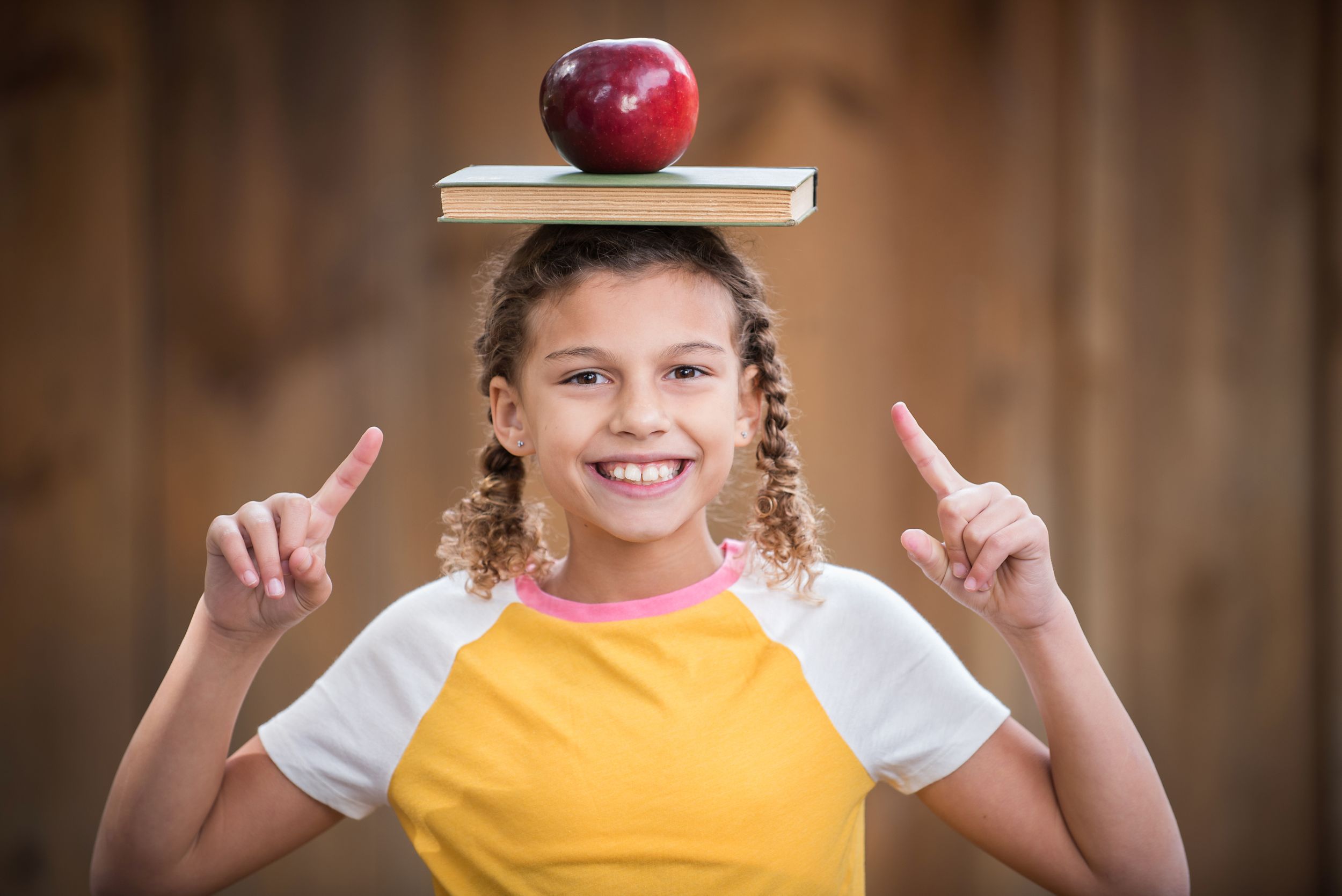 Tween girl back to school look with books and apple balanced on head