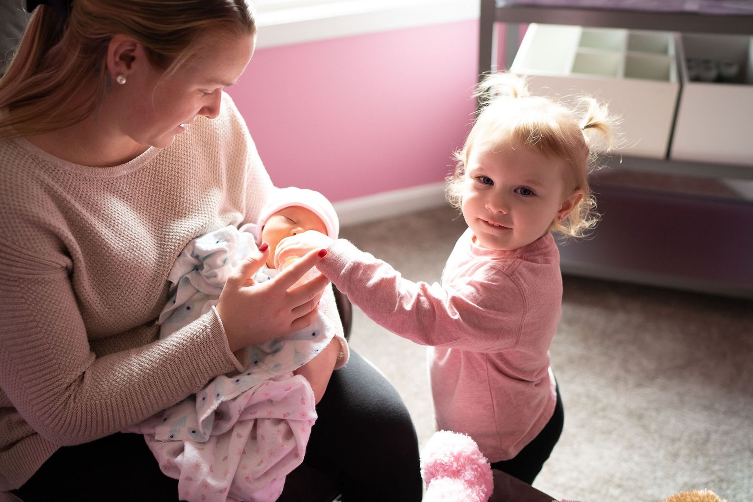 toddler helping feed her baby sister in sudbury ma home