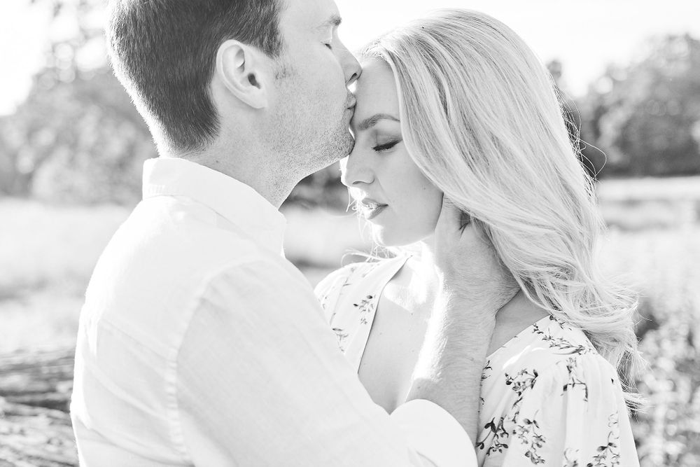 beautiful couple he kisses her on the forehead in wildflower meadow for engagement shoot at Catton Park, Norwich