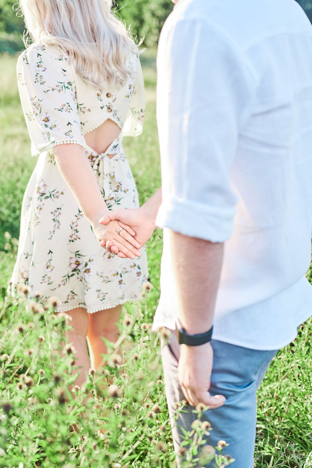 beautiful couple hold hands walking through wildflower meadow for engagement shoot at Catton Park, Norwich
