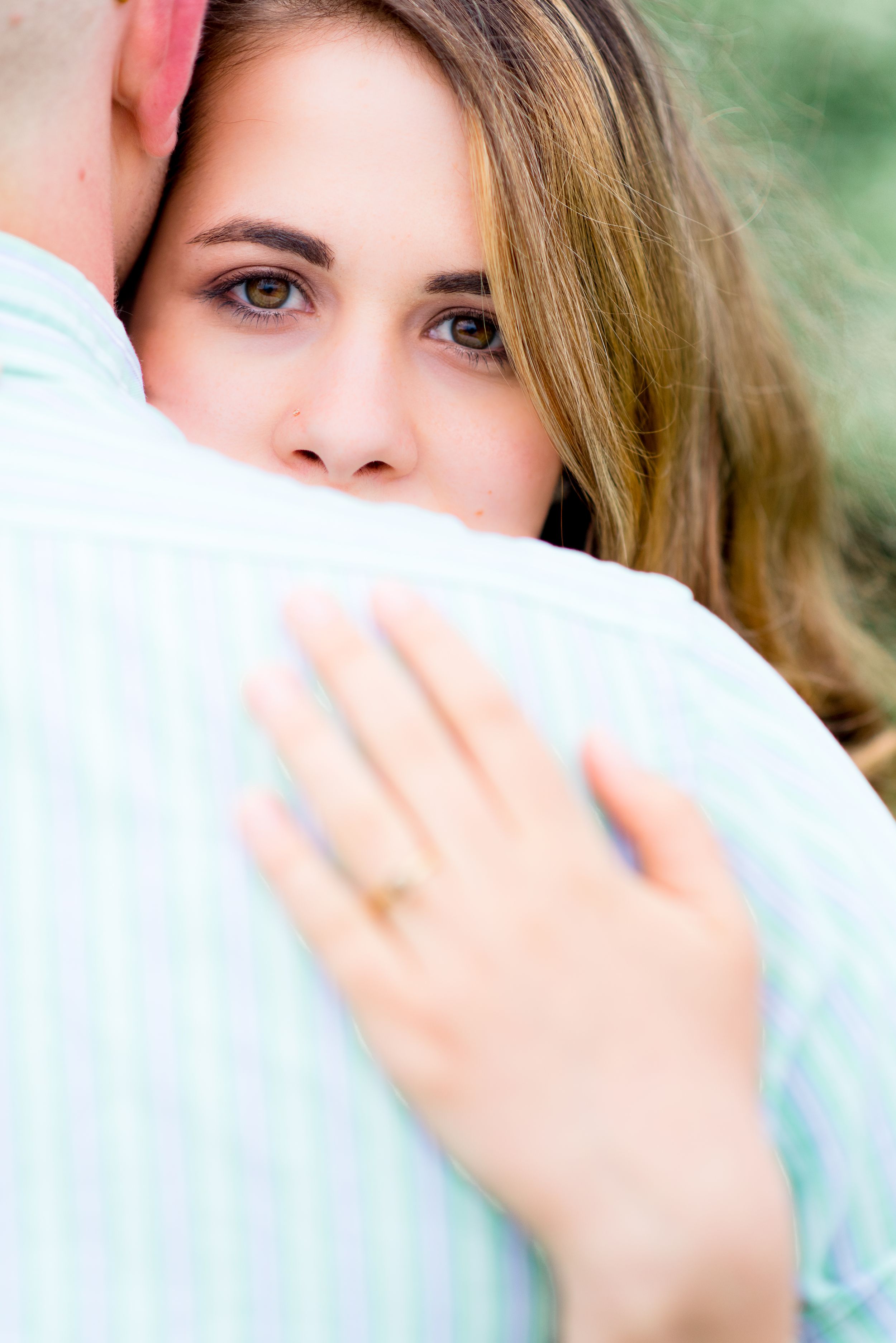 bride peeking over the groom's shoulder showing off her engagement ring at Summer Chicago sunrise engagement pictures