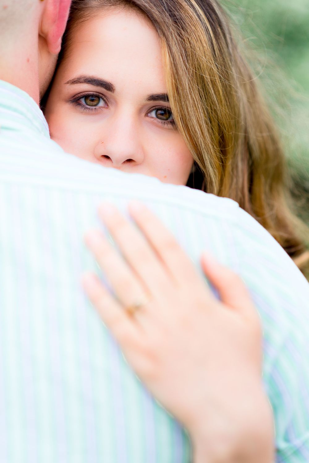 bride peeking over the groom's shoulder showing off her engagement ring at Summer Chicago sunrise engagement pictures