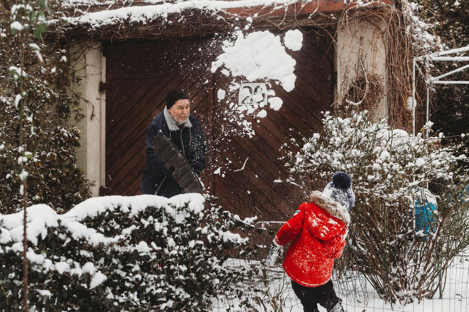 grandad throwing snow at little boy in red jacket