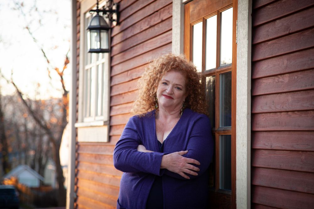 Artistic portrait session against weathered red siding in warm lighting.