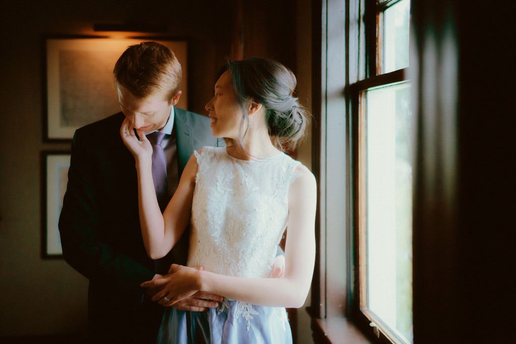 An intimate moment between a couple by a window in moody lighting.