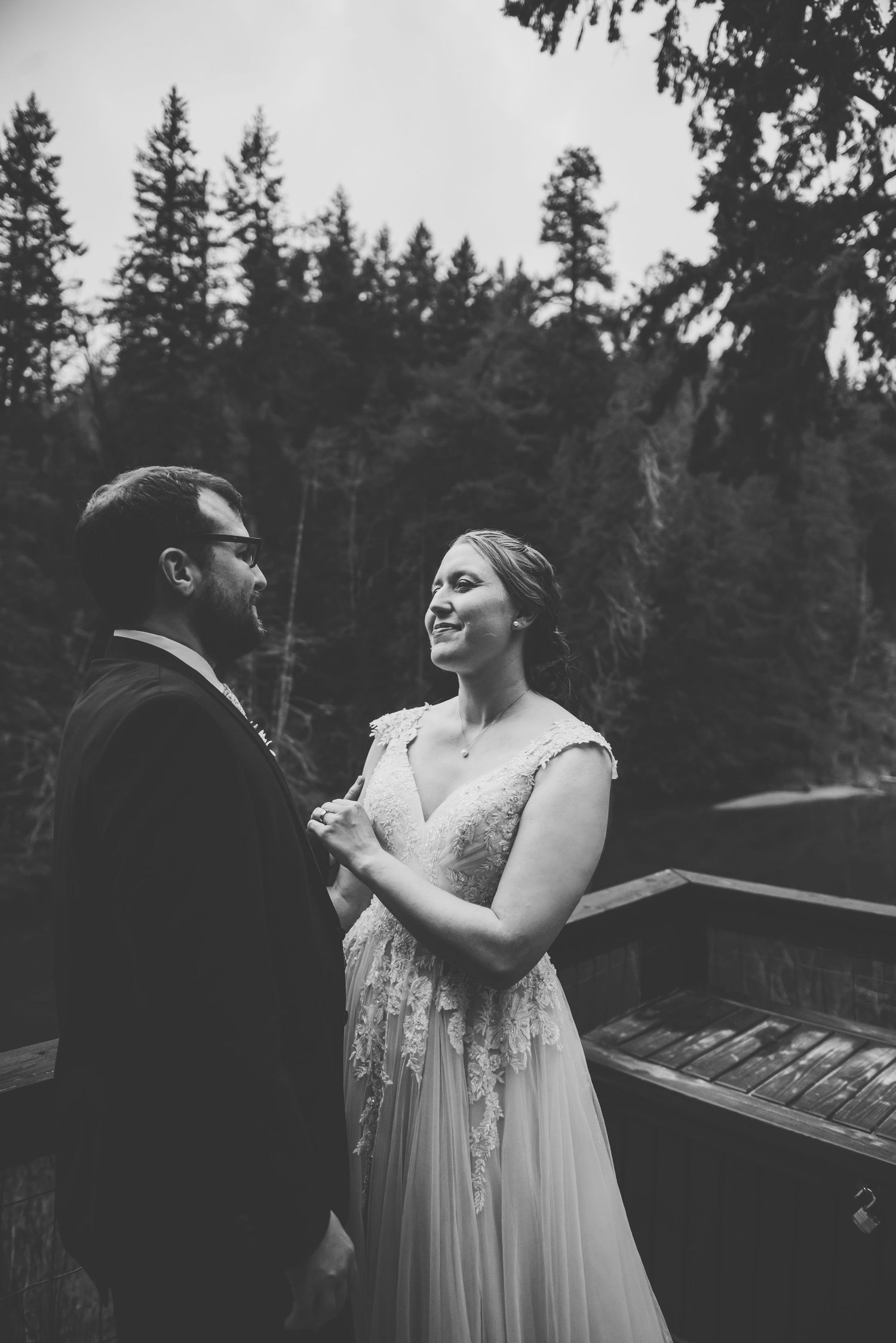 Bride and groom looking lovingly at each other on a patio overlooking shawingan lake, bc.