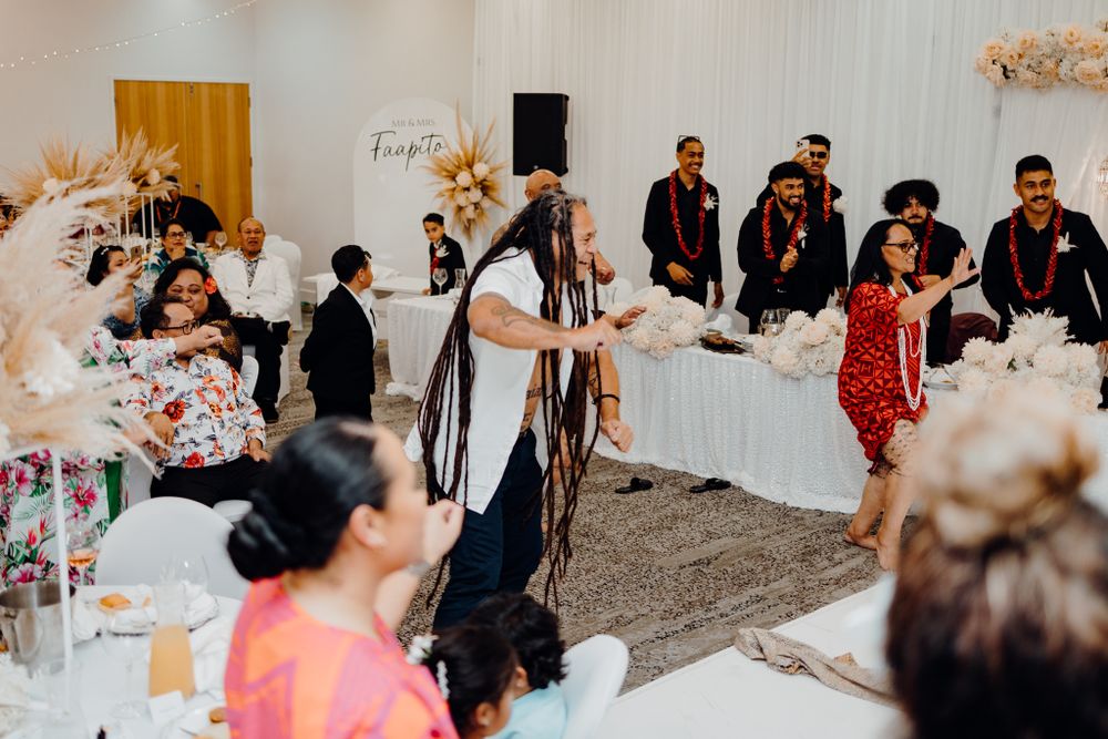 Wedding reception entertainment with dancers performing in front of decorative white backdrop.