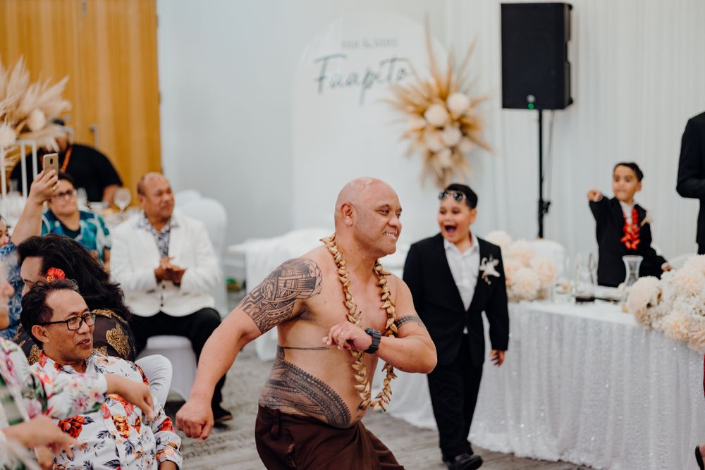 Shirtless performer doing traditional dance at wedding reception.