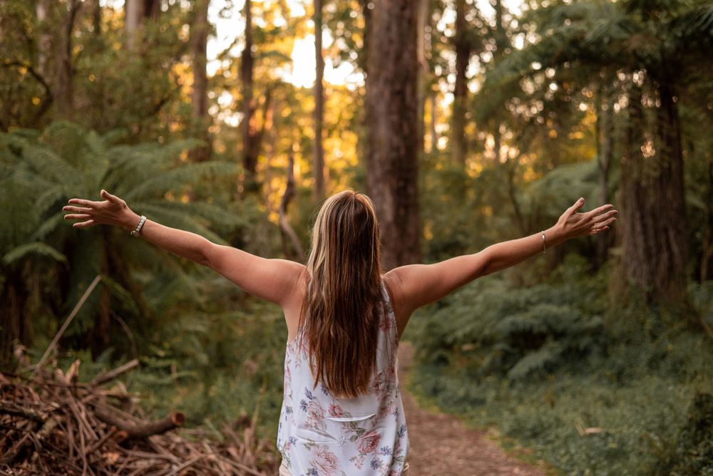Woman photographed from behind with arms outstretched in bush in Melbourne