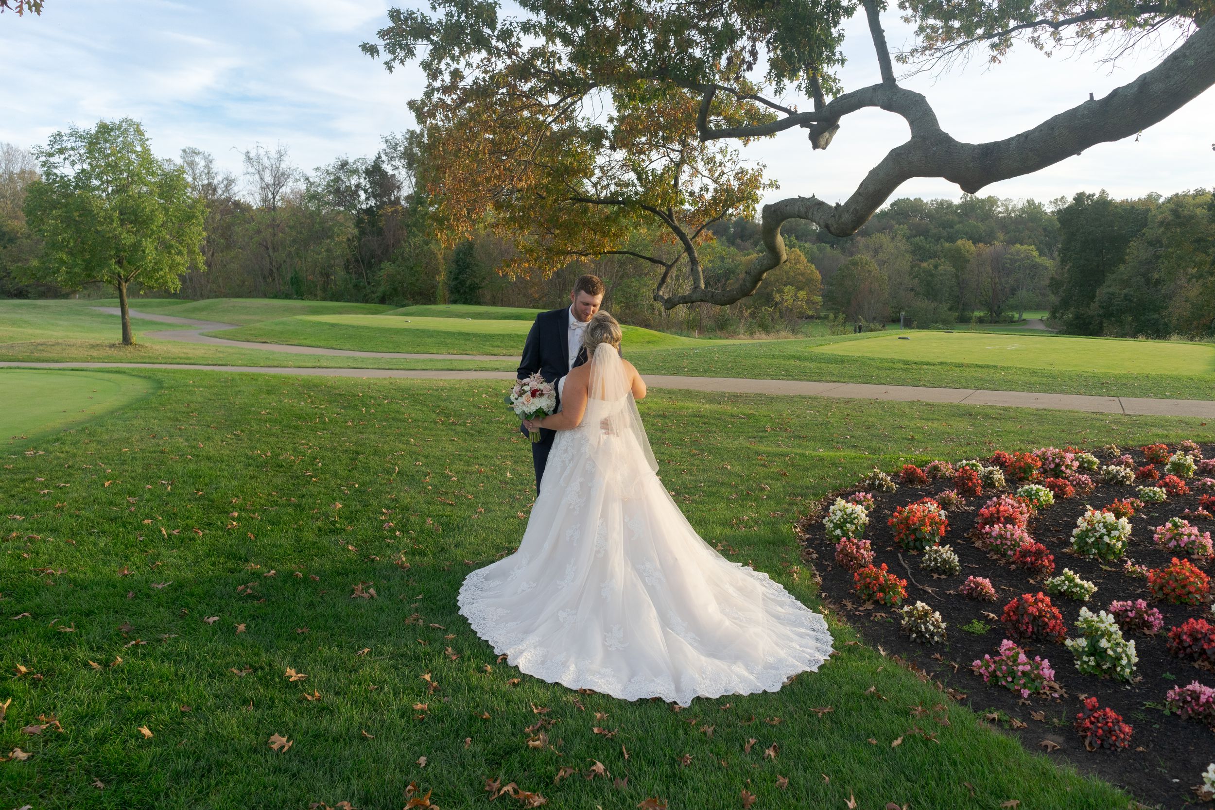 Bride and groom share a picturesque moment on the golf course, blending elegance with natural beauty