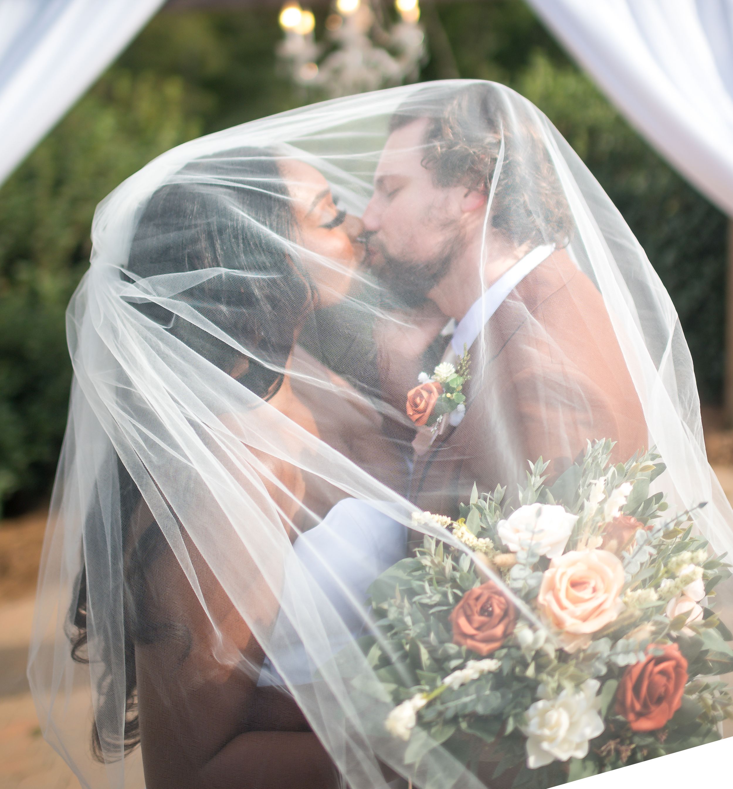 Romantic moment: bride and groom sharing a kiss under a veil, sealing their love with a touch of enchantment.