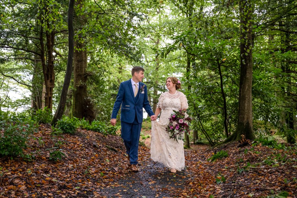 Bride and groom walking in woods at Storrs Hall